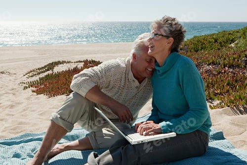 Preview: Mature couple using laptop at the beach