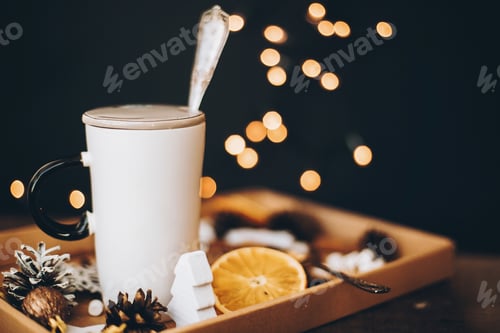 Preview: White cup, christmas decoration, dried oranges, pine cones on black background with christmas lights