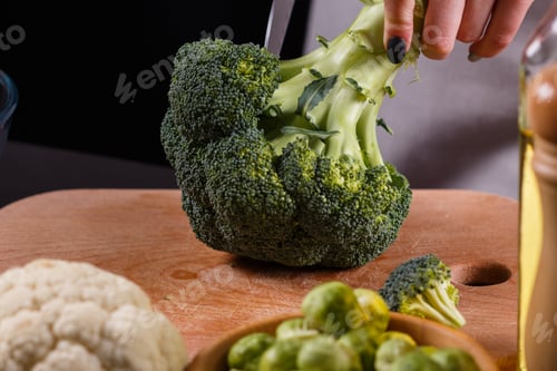 Preview: young woman in a gray aprons cuts cauliflower broccoli