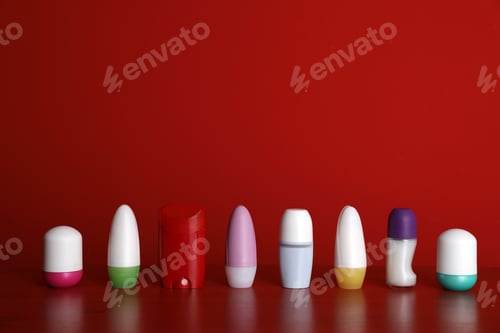 Preview: Different deodorants on table against red background. Space for design