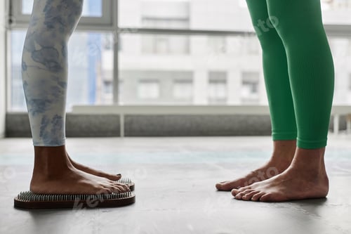 Preview: Black Young Woman Standing on Nail Board in Yoga Studio Against Window