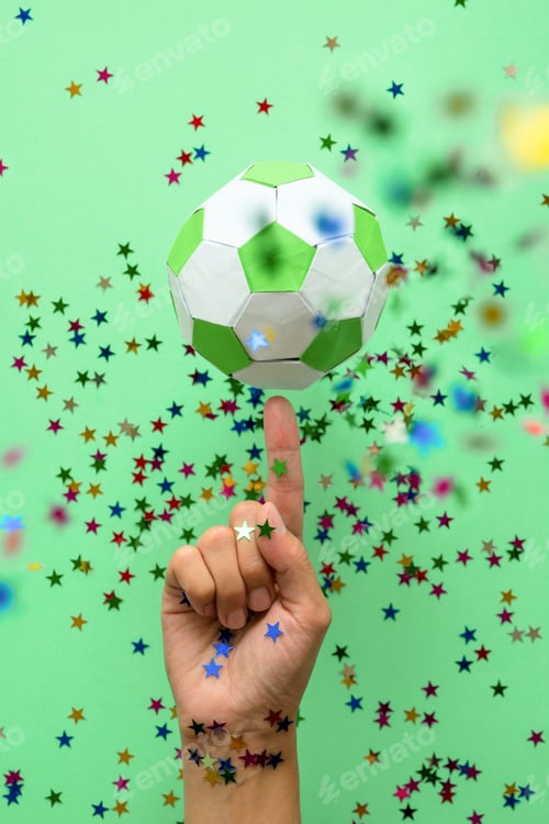 Preview: Hand spinning paper soccer ball on green background. Origami. Paper craft. Soccer game concept.