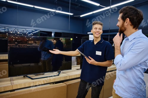 Preview: Sales Associate Expertly Demonstrating Exciting TV Features in a Busy Electronics Store