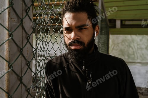Preview: Focused african american sportsman in earphones standing outdoors