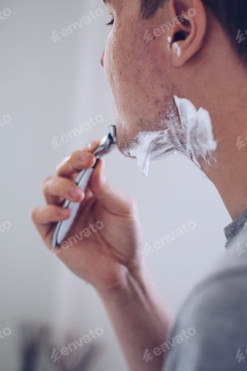 Preview: Young man shaving with a razor