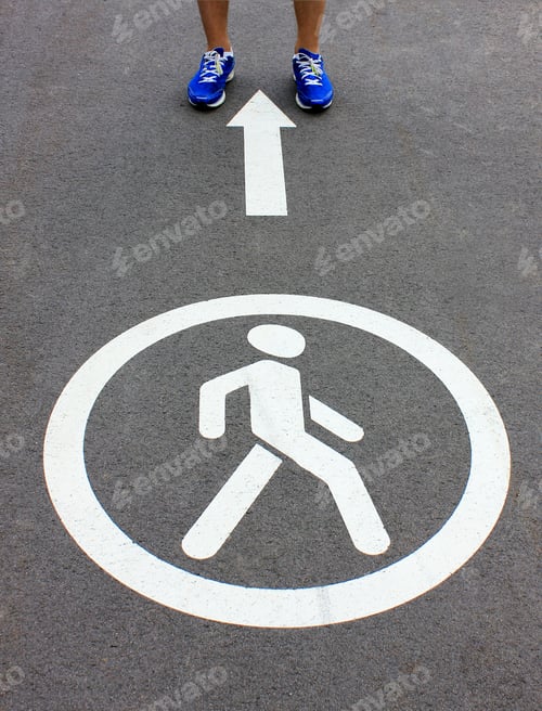 Preview: Man going along road with white arrow and White man Symbol Painted over gray Asphalt.