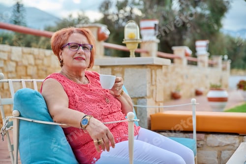 Vorschau: Porträt einer schönen älteren Frau aus den 70ern, die sich mit einer Tasse entspannt.