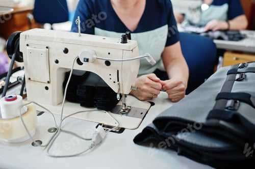 Preview: Female hands stitching fabric on professional manufacturing machine at workplace. Sewing process.
