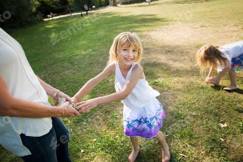 Preview: Mother playing with her daughters in a park.