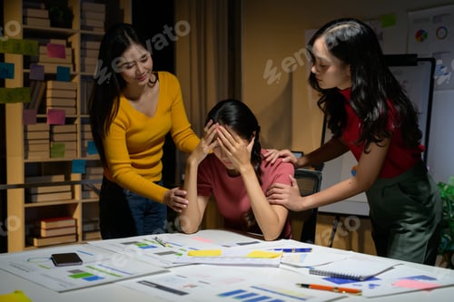 Preview: Concerned Colleagues Comforting Stressed Woman at Work in Office Environment with Documents and Char