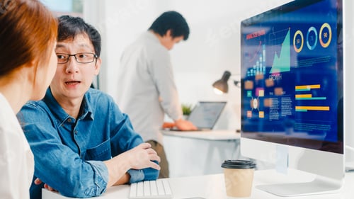 Preview: Young Asia businessman and businesswoman in small modern urban office.