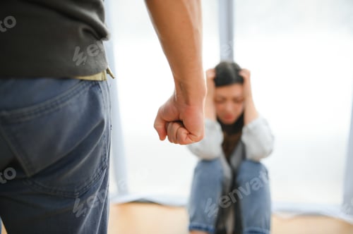 Preview: Quarrel, violence and husband beats wife at home. Angry man raises his fist at frightened woman.