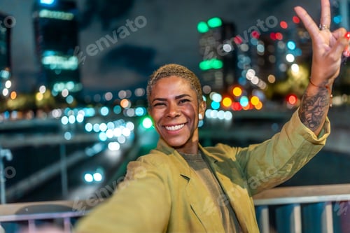 Preview: Happy young woman taking selfie showing peace sign