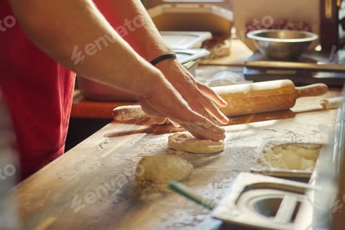 Preview: Hands of male baker with flour dough preparing food on wooden table