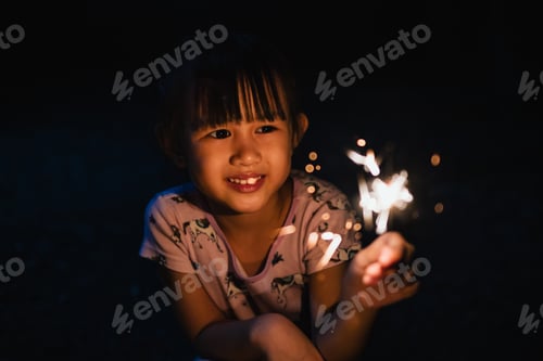 Preview: Young Child Smiles Holding Sparkler in the Dark