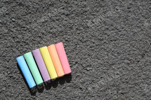 Preview: Colorful chalk sticks on asphalt, flat lay. Space for text
