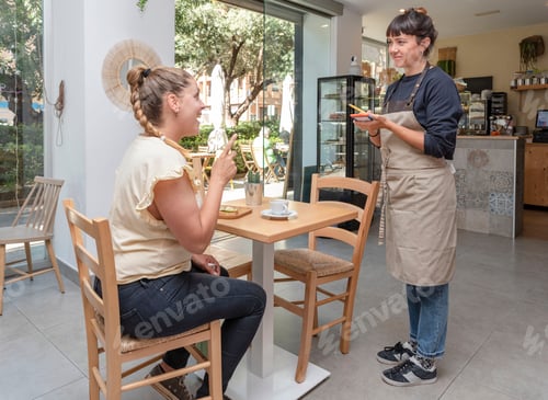 Preview: a young waitress taking an order from a customer in a cafeteria or bar