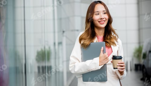 Preview: Smiling Young Woman Holding Laptop in City