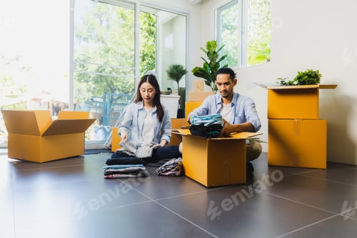Preview: love Asian couple fold cloths into box or take it out to prepare moving new house.