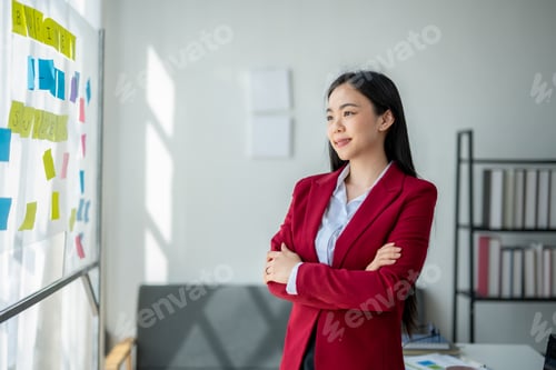 Preview: A woman in a red suit stands in front of a white board with colorful sticky note