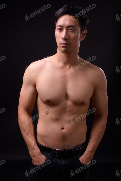 Preview: Young handsome Asian man shirtless against black background