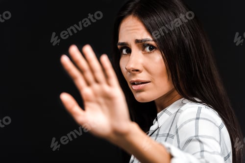 Preview: selective focus of upset woman gesturing while looking at camera isolated on black