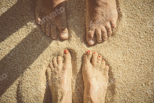 Preview: Feet of a couple standing in the sand seen from above