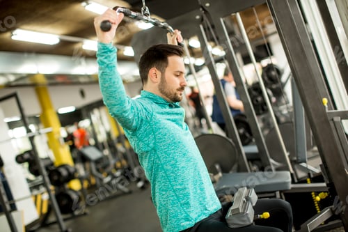 Preview: Young man doing exercise for triceps in the gym on mashine