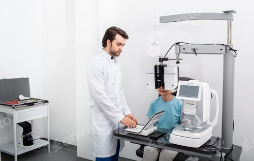 Preview: Serious experienced optometrist doing site testing for a patient using a modern phoropter at a
