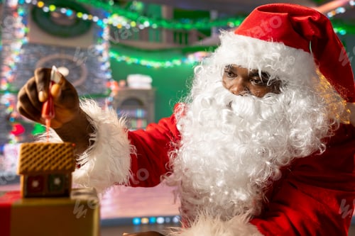 Preview: Father Christmas decorates homemade gingerbread house with frosting and beads