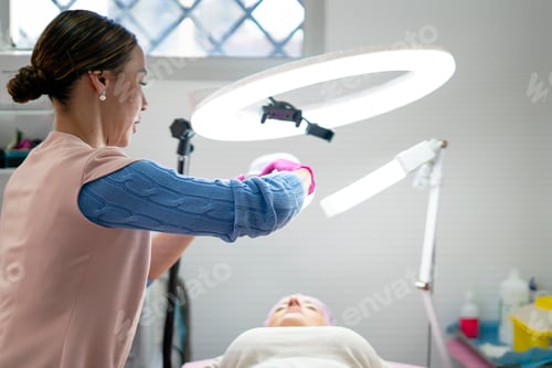 Preview: Beautician preparing lighting equipment for facial treatment in beauty salon