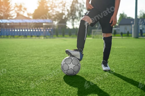 Preview: An unnamed man stands with his foot on a soccer ball in a stadium
