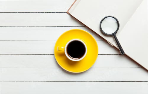 Preview: Cup of coffee and book with loupe on wooden table.