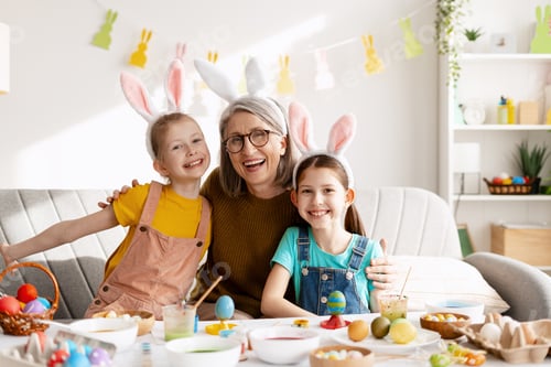 Preview: Grandmother, grandchildren wearing bunny ears, celebrating Easter, decorating eggs