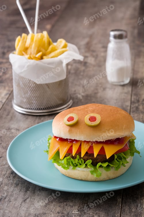 Preview: Monster halloween burger with french fries and salt shaker on wooden table