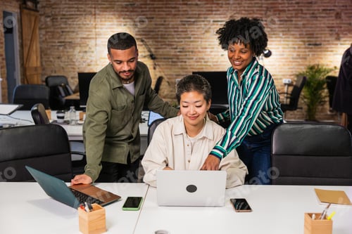 Preview: Multi ethnic team collaborating on laptop in modern office
