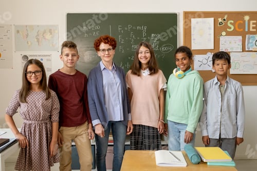 Preview: Row of happy young teacher and schoolchildren standing by blackboard