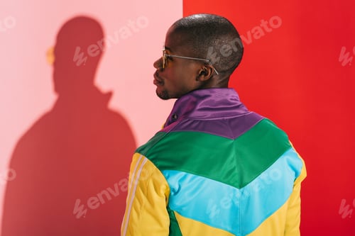 Preview: back view of stylish african american man in colorful jacket and sunglasses looking away