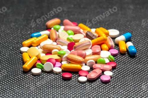 Preview: Collection of colorful pills and tablets scattered on a dark surface