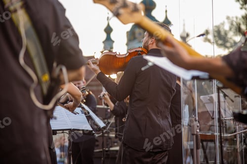 Preview: Male musician playing violin in orchestra outdoors