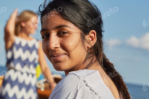 Preview: Young woman looking over shoulder at camera smiling