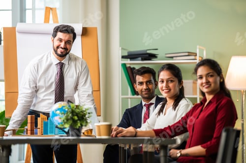 Preview: Indian young businesspeople using laptop in group meeting at desk