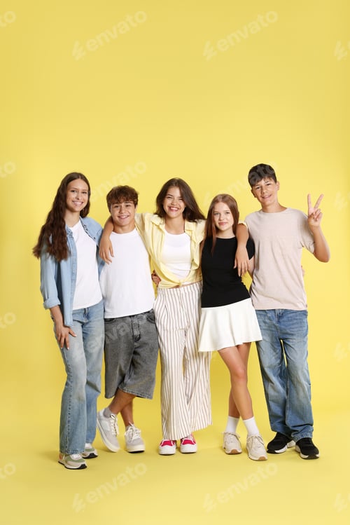 Preview: Full-length portrait of happy teenage friends on yellow background