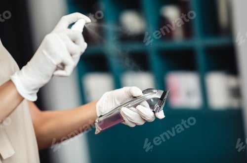 Preview: Close up of hairdresser disinfecting electric trimmer after work