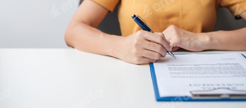 Preview: Woman Signs Document at Desk in Workplace