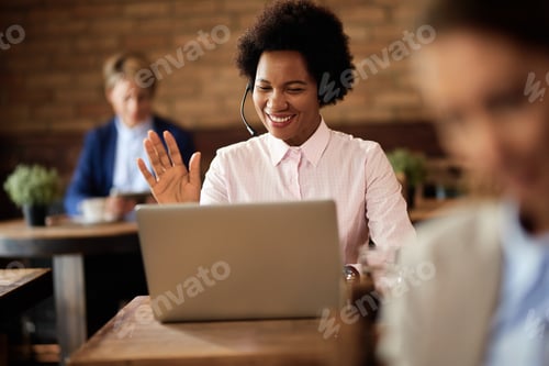 Preview: Happy African American businesswoman having video call over laptop in a cafe.