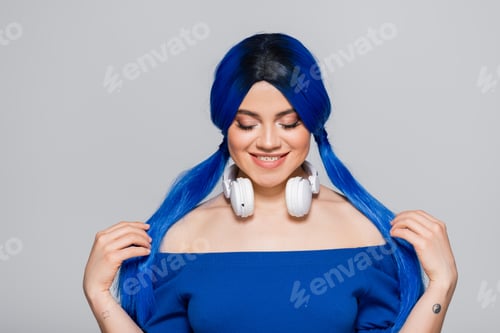 Preview: music lover, happy young woman with blue hair and wireless headphones