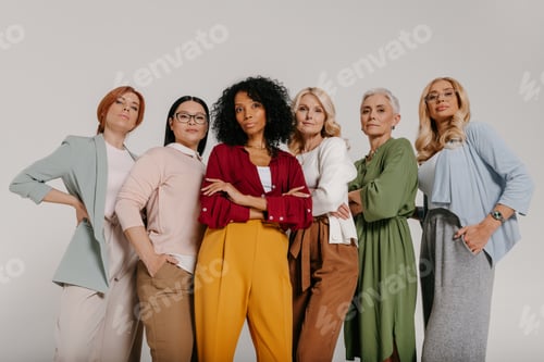 Preview: Low angle view of confident mature women looking at camera against grey background