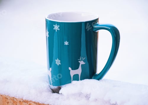 Preview: A mug with hot tea on a deck railing in a snow