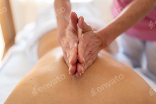 Preview: Crop osteopath massaging back with hands in salon